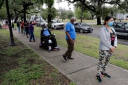 People on foot and in cars line up for food at a food distribution point for people economically impacted by the coronavirus pandemic, organized by New Orleans City Councilman Jay Banks, in New Orleans, April 29, 2020.