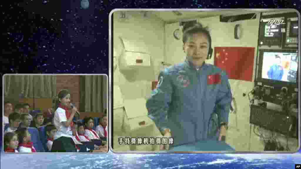 Dalam foto yang diambil dan dibuat dari kamera pengintai atau CCTV, astronot China Wang Yaping, mendengarkan pertanyaan dari seorang siswi di Beijing dalam siaran langsung dari stasiun antariksa prototipe 1 Tiangong (20/6).