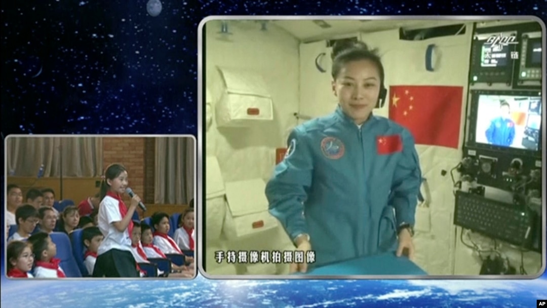 Dalam gambar yang diambil dari kamera CCTV, astronot perempuan China, Wang Yaping (nampak pada layar) sedang mendengarkan pertanyaan dari seorang pelajar putri di Beijing, China, dalam siaran langsung yang dipancarkan dari pesawat antariksa Tiangong-1 (20/6).