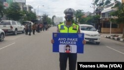 Seorang anggota Polisi dalam operasi Yustisi di Jalan Wolter Monginsi Kota Palu kampanyekan penggunaan masker untuk protokol kesehatan. Kamis, 24 September 2020. (Foto: Yoanes Litha/VOA)