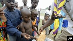 A man distributes bread to children at Abidjan's St. Ambrose church, a temporary refuge for people who fled from clashes between forces loyal to incumbent president Laurent Gbagbo and his rival Alassane Ouattara (File)