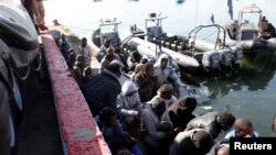 Para migran duduk di pelabuhan, setelah diselamatkan dari laut oleh penjaga pantai Libya di Tripoli (11/4). 