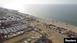 Foto udara menunjukkan warga Palestina berkumpul di pantai menunggu bantuan kemanusiaan yang dijatuhkan dari udara di Gaza, di tengah konflik Israel dan Hamas, di kota Deir Al-Balah, Jalur Gaza tengah. 