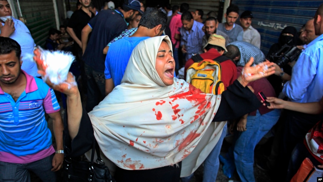 Seorang perempuan yang pakaiannya berlumuran darah menjerit saat terjadi bentrokan antara pasukan pemerintah dan pendukung presiden terguling Mohamed Morsi, Jumat (16/8)