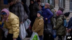 Sergei, 11, mengantre giliran untuk mendapatkan bantuan makanan yang didistribusikan di Bucha, pinggiran Kota Kyiv, Ukraina, pada 19 April 2022. (Foto: AP/Emilio Morenatti)