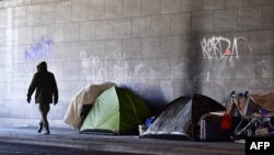 Un homme passe devant des tentes dans un campement improvisé des sans-abris dans le quartier de Tiergarten à Berlin, Allemagne, 1er mars 2018.