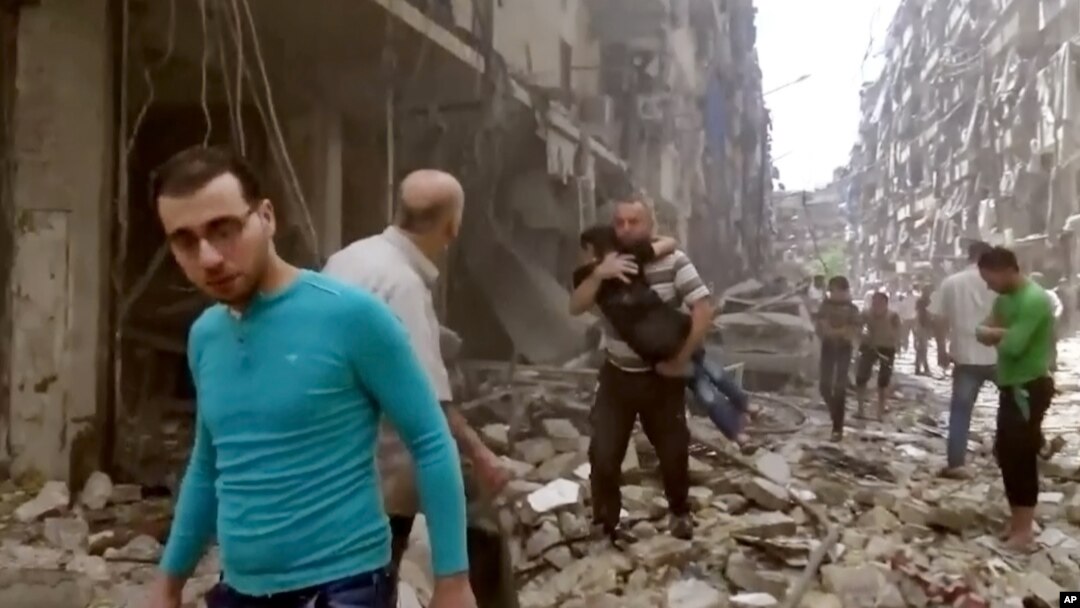 Warga di antara puing-puing bangunan yang rusak karena serangan udara di Aleppo (28/4).