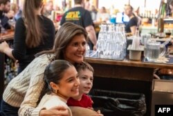 FILE - Republican presidential hopeful and former UN Ambassador Nikki Haley poses with kids for pictures at the Holy Grail, a restaurant and pub in Epping, New Hampshire on January 21, 2024.