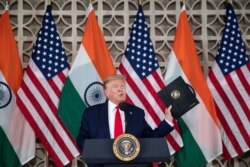 U.S. President Donald Trump holds up his prepared speech that he didn't use as he speaks with business leaders at a roundtable event at Roosevelt House, Feb. 25, 2020, in New Delhi, India.
