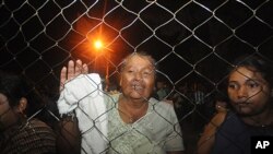 Inmates' relatives stand at the gates of the prison in Comayagua, Honduras, after a fire broke out inside the prison early Wednesday, Feb. 15, 2012.