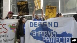 En esta imagen del 12 de marzo de 2018, simpatizantes de los inmigrantes beneficiarios del TPS, sostienen pancartas y gritan consignas durante una marcha previa a una conferencia de prensa en la que se anunció una demanda en contra del gobierno del presidente Donald Trump por su decisión de poner fin a un programa que les permite a los inmigrantes vivir y trabajar legalmente en los Estados Unidos, fuera de una corte federal en San Francisco. (AP Foto/Jeff Chiu, Archivo) 