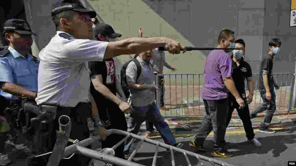 Un policier essaie de stopper un home qui démonte les barricades métalliques que des manifestants ont érigées pour bloquer la route au centre du district économique de Hong Kong, le 13 octobre 2014. (AP Photo/Vincent Yu) 