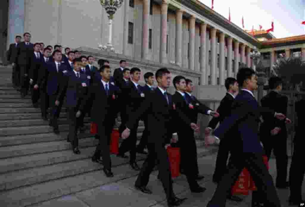 Security guards carrying fire resistant blankets in red pouches leave after the third plenary session of the Chinese People's Political Consultative Conference at the Great Hall of the People in Beijing, China, Saturday, March 10, 2012. (AP Photo/Ng Han 