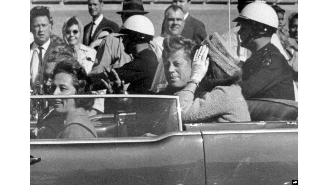 FILE - President John F. Kennedy waves from his car in a motorcade approximately one minute before he was shot, Nov. 22, 1963, in Dallas.