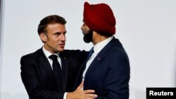 FILE - French President Emmanuel Macron speaks with World Bank President Ajay Banga as they take part in a round table to discuss the global economy during the New Global Financial Pact Summit at the Palais Brongniart in Paris, France on June 22, 2023.