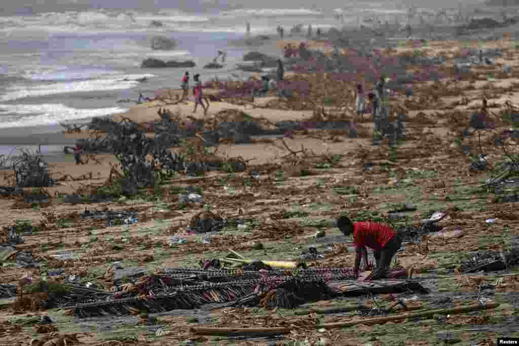 A boy searches among debris on the beach, in the aftermath of Cyclone Batsirai, in the town of Mananjary, Madagascar.