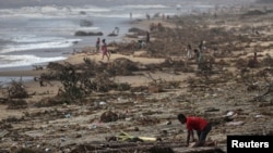 FILE - A boy searches among debris on the beach, in the aftermath of Cyclone Batsirai, in the town of Mananjary, Madagascar, Feb. 8, 2022.