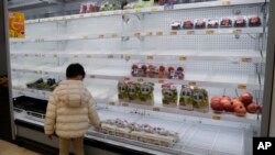 Seorang anak laki-laki melihat rak buah-buahan dan sayuran yang hampir kosong di sebuah supermarket di Hong Kong, pada 8 Februari 2022. (Foto: AP/Kin Cheung)