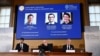 Announcers of the laureates for the Nobel Prize in Chemistry look on as the images of the winners, David Baker, Demis Hassabis and John M Jumper are displayed, in Stockholm, Oct. 9, 2024. (TT News Agency/Christine Olsson via Reuters)