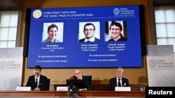 Announcers of the laureates for the Nobel Prize in Chemistry look on as the images of the winners, David Baker, Demis Hassabis and John M Jumper are displayed, in Stockholm, Oct. 9, 2024. (TT News Agency/Christine Olsson via Reuters)