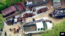 This photo from video provided by KCBS/KCAL-TV shows investigators from the U.S. Bureau of Alcohol, Tobacco, Firearms and Explosives and the police inspecting a large cache of weapons seized at a home in the affluent Holmby Hills area of Los Angeles, May 8, 2019.