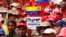 FILE - A demonstrator holds a sign with a message that reads in Spanish: "Trump unblock Venezuela" as members of the Bolivarian militia attend a protest against U.S. sanctions on Venezuela, in Caracas, Venezuela, Aug. 7, 2019. 