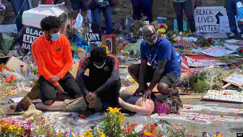 Tres hombres negros y un hombre blanco interpretan el arresto de George Floyd en un altar recordatorio improvisado en Minneapolis, Minnesota, el 1 de junio de 2020. 