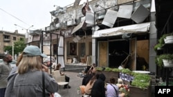 Teman dan kerabat dari para korban yang meninggal dalam serangan Rusia di sebuah restoran di Kramatorsk, Ukraina, berkumpul mengenang para korban di depan restoran yang kini hancur pada 29 Juni 2023. (Foto: AFP/Genya Savilov)