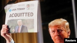 U.S. President Donald Trump holds up a copy of USA Today's front page showing news of his acquitttal in his Senate impeachment trial, as he arrives to address the National Prayer Breakfast in Washington, U.S., February 6, 2020. REUTERS