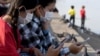 FILE - This photo taken on February 4, 2022, shows students using their smartphones while seated along the riverside in Phnom Penh.