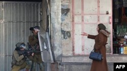 A woman gestures at Israeli security forces firing rubber bullets to break up Palestinian stone-throwers during clashes in the West Bank town of Hebron.