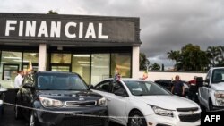 FILE - People look at cars at a pre-owned car sales lot in Miami, Florida. Taken 1.12.2022