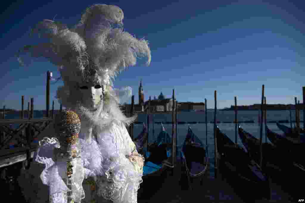 A masked reveler wearing a traditional carnival costume poses in St Mark Square during Venice&#39;s Carnival, Italy, Feb. 12, 2022.