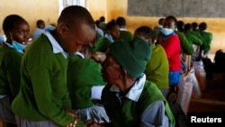 Priscilla Sitienei greets her schoolmate at the Leaders Vision Preparatory School, January 25, 2022. REUTERS/Monicah Mwangi
