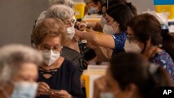 Algunas mujeres reciben la cuarta dosis de la vacuna de Pfizer contra COVID-19 como parte de una segunda campaña de vacunas de refuerzo contra el nuevo coronavirus, en una instalación deportiva en Santiago, Chile, el 7 de febrero de 2022. 