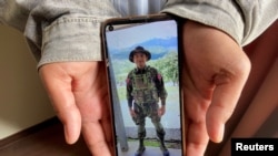 Kaung Thu Win, who said he served as a captain in Myanmar's military before defecting in late December, shows a photograph of himself wearing an army uniform on his mobile phone, during an interview with Reuters at an undisclosed location in northeastern India, Jan. 21, 2022.