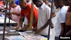 FILE - Civilians read newspapers on display in Dar es Salaam, Tanzania, March 18, 2021. 