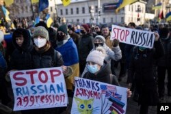 Demonstrators with Ukrainian national flags and posters march in the center of Kharkiv, Ukraine's second-largest city, Feb. 5, 2022, just 40 kilometers from some of the tens of thousands of Russian troops massed at the border of Ukraine.