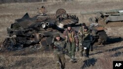 Separatistas respaldados por Rusia caminan después de inspeccionar los tanques destruidos del ejército ucraniano en busca de armas funcionales y municiones cerca de la aldea de Lohvynove, en las afueras de Debaltseve, Ucrania, el 22 de febrero de 2015.