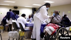 FILE - A woman gets a COVID-19 vaccine as South Africa rolls out coronavirus disease vaccinations to the elderly at the Munsieville Care for the Aged Centre outside Johannesburg, South Africa, May 17, 2021.