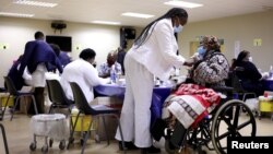 FILE - A woman gets a COVID-19 vaccine as South Africa rolls out coronavirus disease vaccinations to the elderly at the Munsieville Care for the Aged Centre outside Johannesburg, South Africa, May 17, 2021.