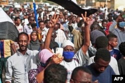 A man holds up his arms showing the "V" gesture with his fingers while marching during a demonstration calling for civilian rule and denouncing the military administration, in the south of Sudan's capital Khartoum, Feb. 10, 2022.