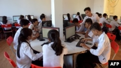 FILE - This file photo taken on June 26, 2018, shows Cambodian students and a teacher using computers in a modern classroom built under Prime Minister Hun Sen's administration campaign for the "new generation" school's program in Phnom Penh. (Photo by TANG CHHIN Sothy / AFP)