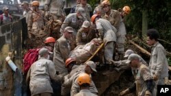 Rescue workers remove the body of a mudslide victim in Petropolis, Brazil, Feb. 16, 2022. 