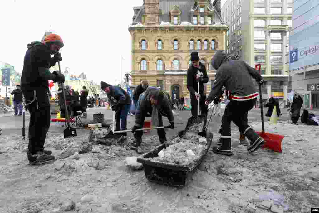 Protesters and supporters clear snow and ice in front of Prime Minister Justin Trudeau&#39;s office as demonstrators continue to protest the vaccine mandates, in Ottawa, Canada.