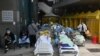 Para pasien berbaring di ranjang di luar sebuah rumah sakit, karena penuhnya kamar-kamar rumah sakit di Hong Kong Selasa (15/2), sementara kota itu menghadapi lonjakan pandemi COVID-19 terburuk saat ini. (Foto: AFP)