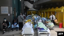 Para pasien berbaring di ranjang di luar sebuah rumah sakit, karena penuhnya kamar-kamar rumah sakit di Hong Kong Selasa (15/2), sementara kota itu menghadapi lonjakan pandemi COVID-19 terburuk saat ini. (Foto: AFP)