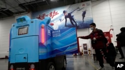 A worker opens the door of a delivery robot at the Main Distribution Center built to provide logistic support for the Beijing Winter Olympics in Beijing, China, Thursday, Dec.  9, 2021 (AP Photo / Ng Han Guan)