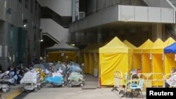 Patients wearing face masks lie in bed at an area outside a hospital, during the COVID-19 outbreak in Hong Kong, China, Feb. 15, 2022.