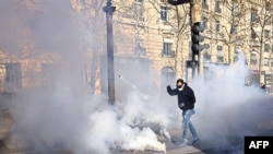 프랑스 파리에서 시위대가 최루탄을 발로 차고 있다.